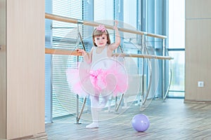 Little ballerina girl in a pink tutu. Adorable child dancing classical ballet in a white studio. Children dance. Kids