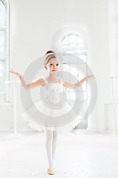 Little ballerina girl in a tutu. Adorable child dancing classical ballet in a white studio.