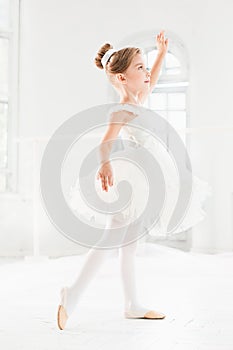 Little ballerina girl in a tutu. Adorable child dancing classical ballet in a white studio.