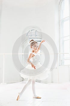 Little ballerina girl in a tutu. Adorable child dancing classical ballet in a white studio.