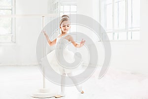 Little ballerina girl in a tutu. Adorable child dancing classical ballet in a white studio.