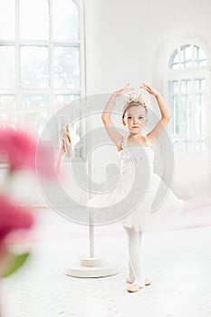 Little ballerina girl in a tutu. Adorable child dancing classical ballet in a white studio.