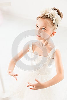 Little ballerina girl in a tutu. Adorable child dancing classical ballet in a white studio.