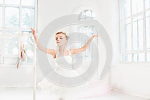 Little ballerina girl in a tutu. Adorable child dancing classical ballet in a white studio.