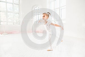 Little ballerina girl in a tutu. Adorable child dancing classical ballet in a white studio.