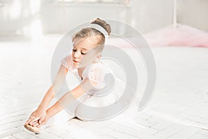 Little ballerina girl in a tutu. Adorable child dancing classical ballet in a white studio.