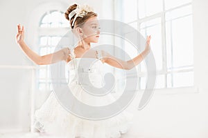 Little ballerina girl in a tutu. Adorable child dancing classical ballet in a white studio.