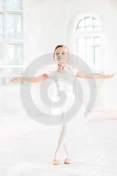 Little ballerina girl in a tutu. Adorable child dancing classical ballet in a white studio.