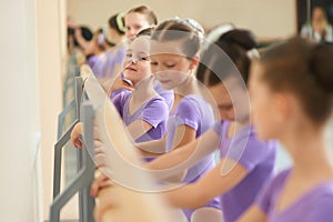 Little ballerina posing near ballet barre.