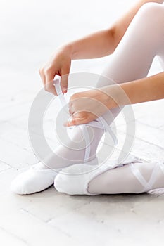 Little ballerina puting on foot pointe shoes
