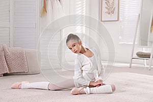 Little ballerina stretching on floor at home