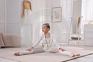 Little ballerina stretching on floor at home