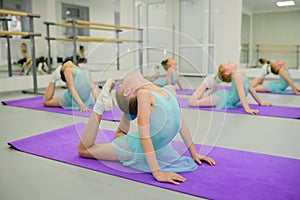 Little ballerinas during stretching exercises in ballet school class