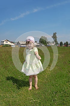 Little barefoot girl plays shows blade of grass