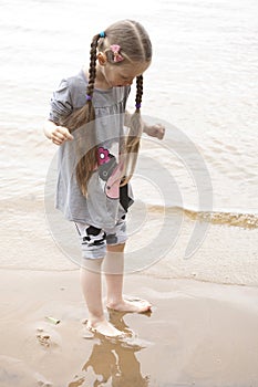 Little barefoot girl standing near the river
