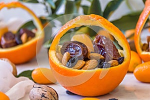 Little basket made of fresh orange filled with dry fruits; almonds, dates, raisins and nuts