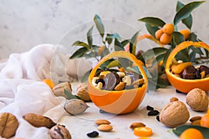 Little basket made of fresh orange filled with dry fruits; almonds, dates, raisins and nuts