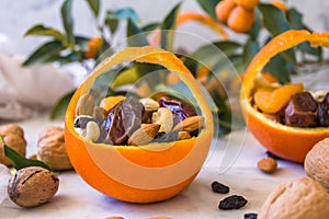 Little basket made of fresh orange filled with dry fruits; almonds, dates, raisins and nuts