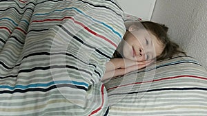 a little beautiful baby lies under a nice warm blanket and falls asleep in her crib.