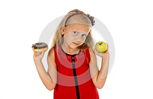 Little beautiful blond child choosing dessert holding unhealthy chocolate donut and apple fruit