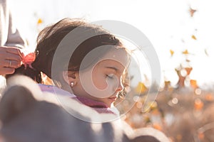 Little beautiful child in a funny hat and scarf holds parent`s hand on a walk outdoors