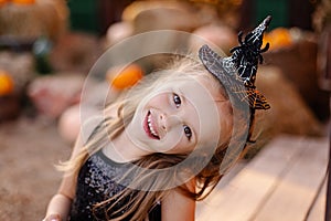 Little beautiful cute girl in witch costume celebrate Halloween portrait. A fun child masquerade on the terrace. little moments ou