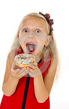 Little beautiful female child with long blonde hair and red dress eating sugar donut with toppings delighted and happy