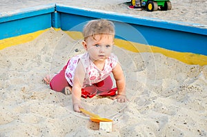 Little beautiful girl baby play in the sandbox and sand toys on the playground