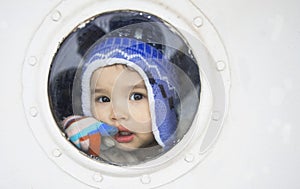 Little beautiful girl behind the ship window