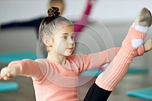 Little beautiful girl, child training, doing stretching exercises indoors. Gracefulness and flexibility. Unfocused