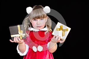 Little beautiful girl in a Christmas Santa suit, with fur balls on her head, holds gifts in her hands and rejoices.