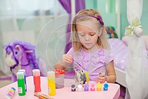 Little beautiful girl draws paints on the table