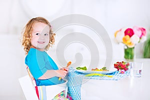 Little beautiful girl eating salad for lunch