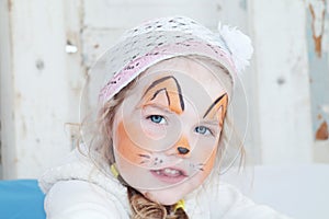 Little beautiful girl with face painting of orange fox