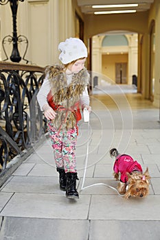 Little beautiful girl held on leash dog in pink