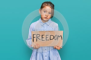 Little beautiful girl holding freedom banner thinking attitude and sober expression looking self confident