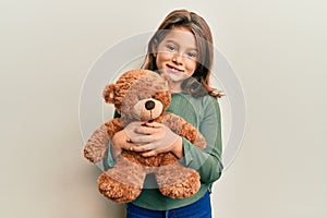 Little beautiful girl hugging teddy bear smiling with a happy and cool smile on face