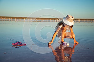 A little beautiful girl is looking at something in a transparent water surface on a transparent background