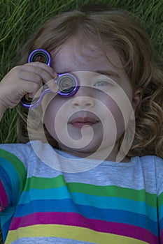 Little beautiful girl is playing blue spinner in hand.