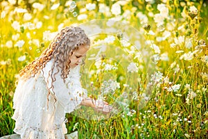 Little beautiful girl playing on the lawn in summer with soap bubbles