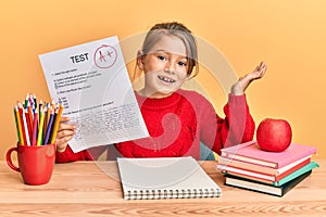 Little beautiful girl showing a passed exam celebrating achievement with happy smile and winner expression with raised hand