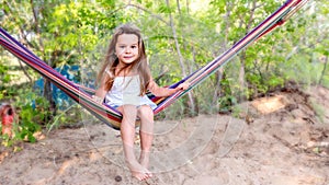 Little beautiful girl sitting in a hammock and smiling