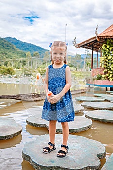 Little beautiful girl standing with a bottle of fish food in hand. Yang Bay Vietnam