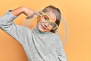 Little beautiful girl wearing casual clothes and yellow glasses smiling happy pointing with hand and finger