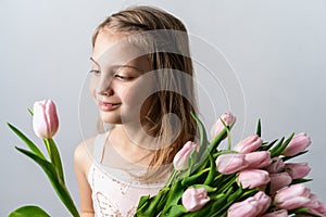 Little beautiful happy girl holding bunch of pink, green tulips in hands. Bouquet, congratulations to the holiday of mother,