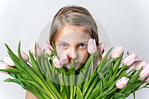 Little beautiful happy girl holding bunch of pink, green tulips in hands. Bouquet, congratulations to the holiday of mother,