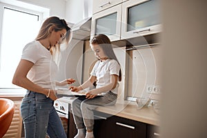 Little beautiful kid helping her mommy to cook cake