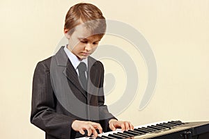 Little beginner musician in suit playing the synthesizer