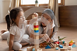 Little biracial baby girl playing cubes with mommy.