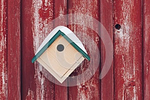 Little bird house on a red wall with a hole
